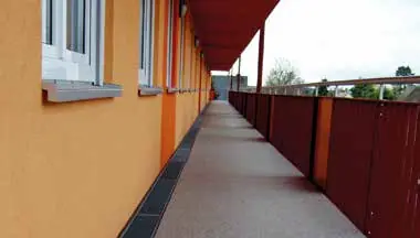 Coursive extérieure d’un immeuble, garde-corps rouge et façade orange