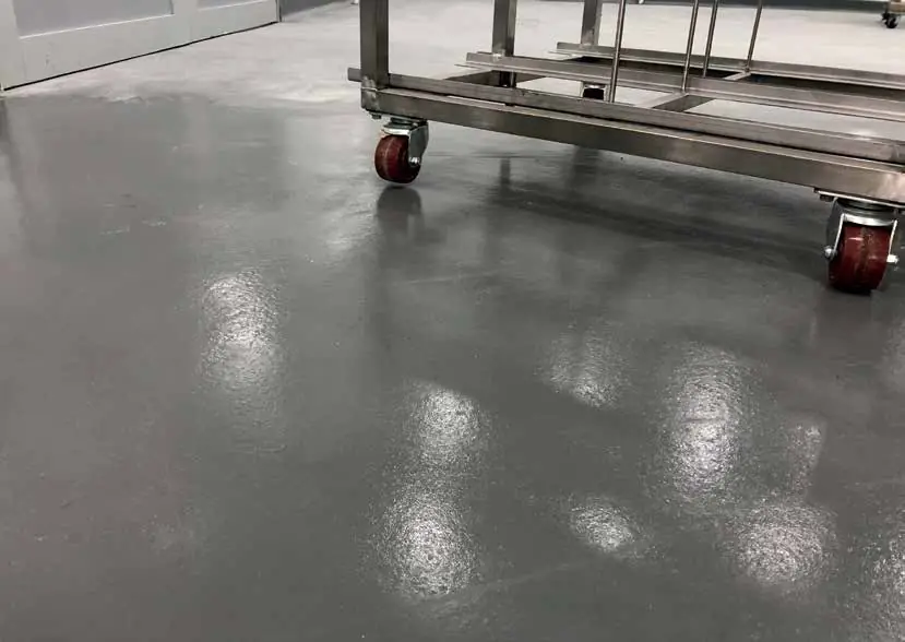 Sol gris brillant et chariot inox sur roulettes dans un atelier de production