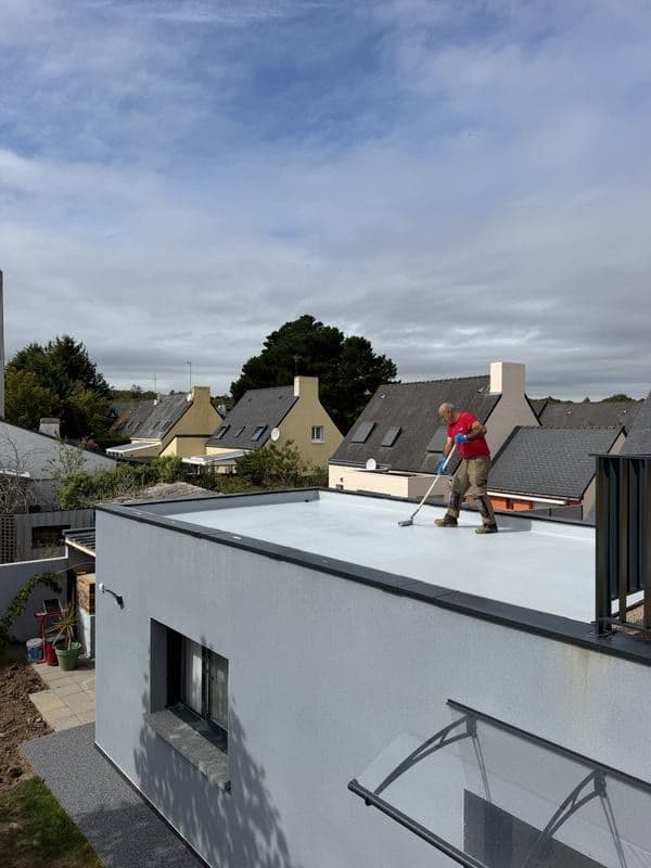 Maison neuve à toit plat à Lanester, applicateur en cours d’étanchéité liquide sur le toit-terrasse