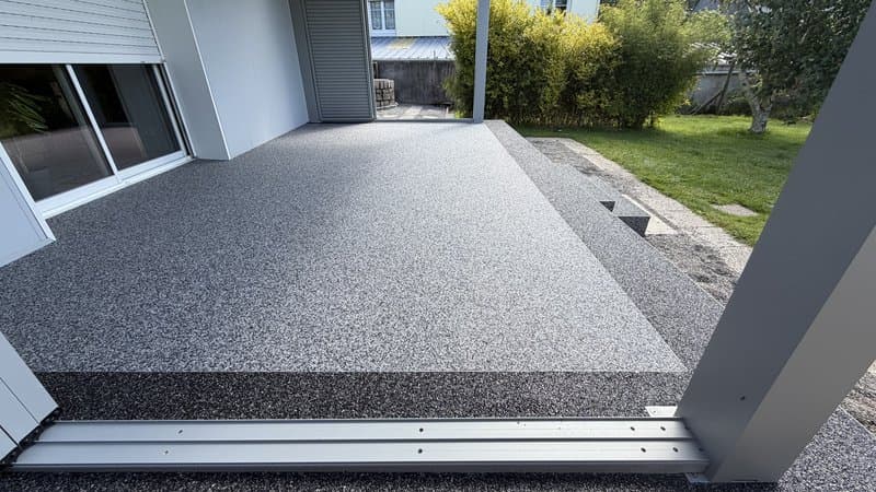 Zoom sur la finition d'une moquette de pierre bicolore drainante en granulat de marbre, contraste gris clair et noir profond