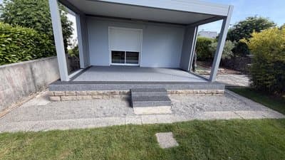 Terrasse résidentielle sous pergola bioclimatique grise avec moquette de pierre bicolore, centre gris clair et bordures noires, Cléguer Morbihan