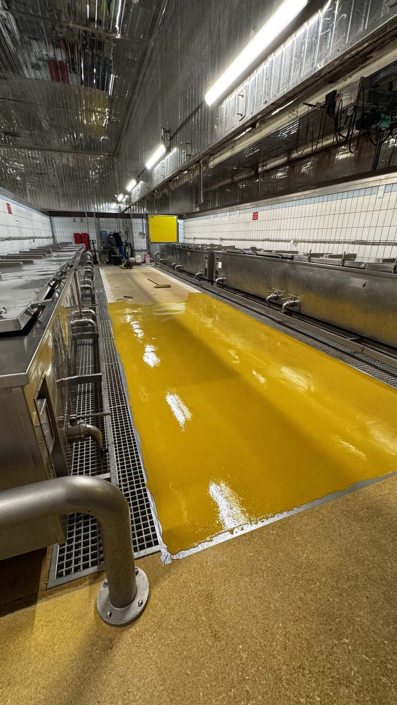 Vue d'ensemble d'un sol résine HACCP en industrie agroalimentaire bretonne, finition résistante aux lavages et produits chimiques